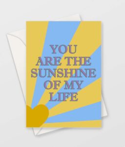Valentine's Card. yellow heart shaped sun with yellow rays on blue sky background and the words "You are the sunshine of my life"